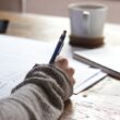 Kobieta w biurze trzymająca certyfikat Cambridge English uśmiechając się pewnie
