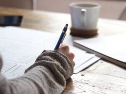 Kobieta w biurze trzymająca certyfikat Cambridge English uśmiechając się pewnie